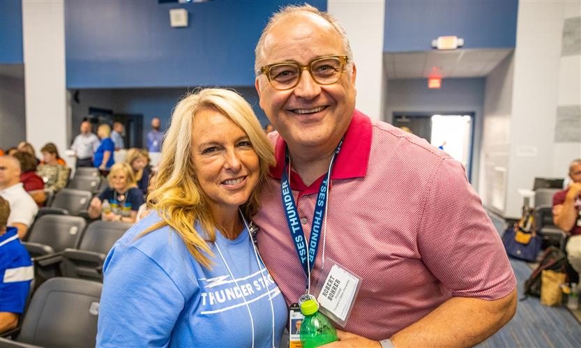 Two administrators lean together and smile
